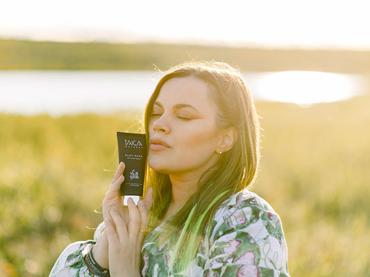 Nainen pitelee käsissään Taiga Cosmeticsin voidetta ulkona syksyisellä pellolla